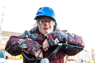 Outdoor portrait of a 39 year old white woman with the Down Syndrome wearing a blue bike helmet