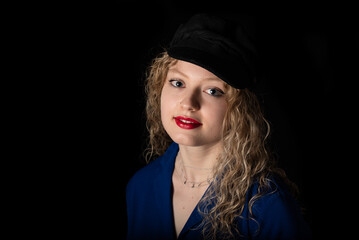 Studio portrait of a 21 year old white blonde woman with curling hair wearing a hat