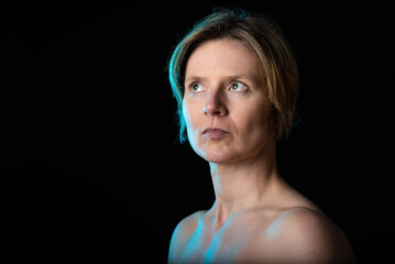 Low key studio portrait of a 35 year old white woman with naked shoulders showing her biceps