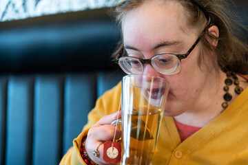Indoor portrait of a 39 year old white woman with the Down Syndrome drinking tea