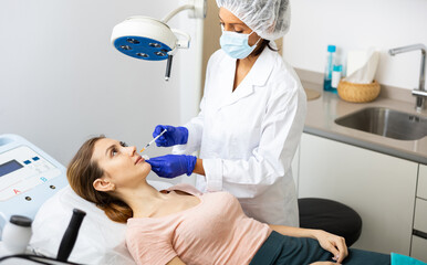 European woman getting procedure of injection contouring and lip augmentation in cosmetology clinic