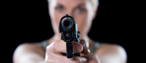 Young woman shooting with the gun isolated on black background.