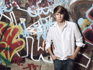 My lifestyle, my choice. Portrait of a trendy teenage boy posing against a spray painted wall.