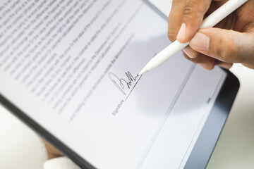 Close up businessman hand electronic Signature on Tablet by Stylus. Write business agreement of contract. Man signing contract on tablet. Business and technology concept.