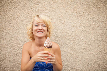 Blonde woman eating ice cream cone dipped in chocolate