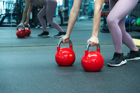 Young woman working out at gym. Attractive woman training in light modern gym. Doing plank on kettlebell. Push-up on weights.
