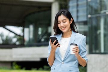 Beautiful business woman using mobile phone to play social media in the buildings at downtown. Smart female using cell phone chatting for business communication. Smartphone concept.