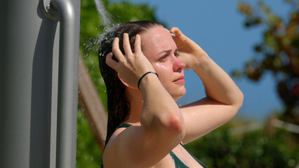 Young woman taking a shower after sun bathing at the beach