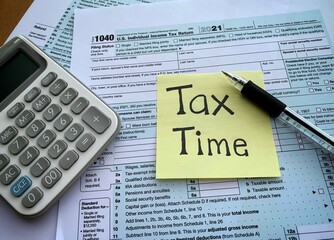 1040 US individual tax form, calculator, pen, and yellow sticker. Tax concept.