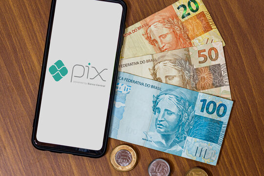 Sao Paulo, Brazil. MARCH 8, 2022: Pix logo on smartphone screen with multiple coins around. Pix is the new payment and transfer system of the Brazilian and Brazilian government.