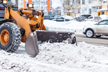 Big orange tractor cleans up snow from the road and loads it into the truck. Cleaning and cleaning...