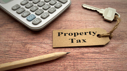 Property Tax text on keychain with calculator, pencil and wooden desk background. Property tax...