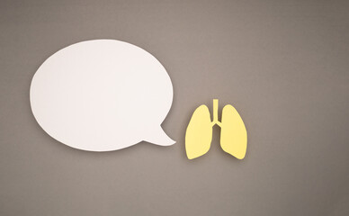 Lungs shape made from yellow paper and a blank speech bubble on a gray background