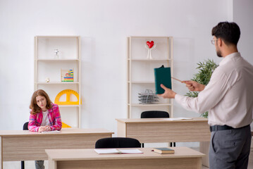 Young male teacher and redhead girl in the classroom