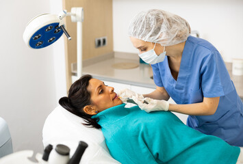 Mexican woman getting procedure of injection contouring and lip augmentation in cosmetology clinic