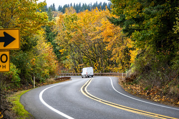 Compact cargo mini van for small business and deliveries running on the winding mountain autumn...