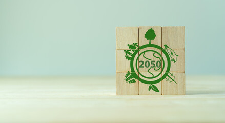 Net zero by 2050. Carbon neutral. Net zero greenhouse gas emissions target. Climate neutral long term strategy. No toxic gases. Hand puts wooden cubes with net zero icon in 2050 on grey background.