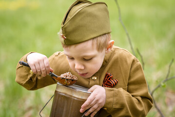 a small child in a beautiful military victory uniform, playing in nature and eating soldier porridge