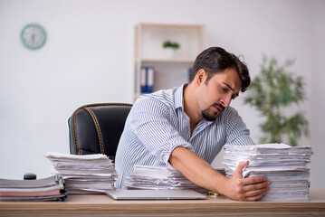 Fototapeta premium Young male employee unhappy with excessive work in the office