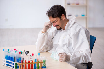 Young male chemist in drugs synthesis concept