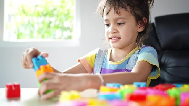 Girls have fun playing with toy puzzles on the table, learning comes from happy play, brain development, creativity.
