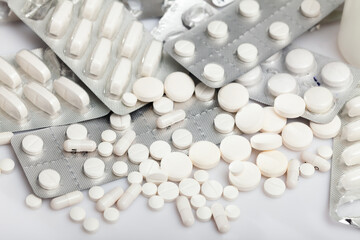 Closeup view of different pills spilled on white background. Medicine and pharmaceutics concept