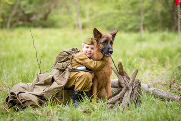 a boy in a military uniform in a clearing, sitting by a campfire with a German shepherd.Two friends...