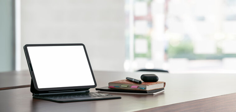 Workspace, mockup open blank screen digital tablet with magic keyboard on wooden desk in office room, banner.