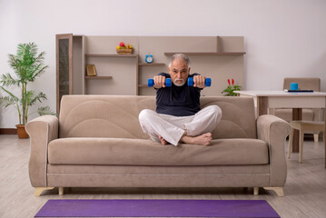 Old man doing sport exercises at home