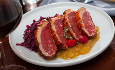 Tasty roasted duck breast Magret with stewed cabbage, herbs and sauces on plate