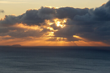 The sun's rays come from behind the clouds