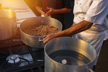 Professional chef giving classes to his student who serves as an assistant