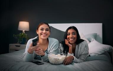 We have everything we need right here. Shot of two young women eating popcorn while watching a...