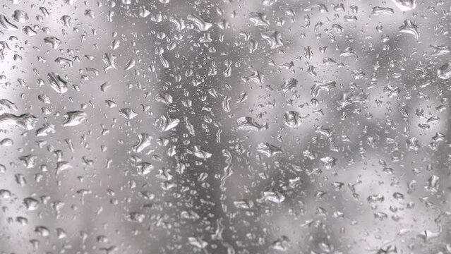Water drops falling down on window car glass. Rain drops on blue window. Raindrops falling in rainy day. Raining, slow motion, close up