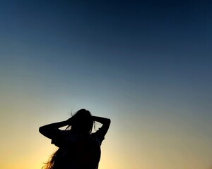 silhouette of a woman in front of blue and yellow sky with space to write your text 