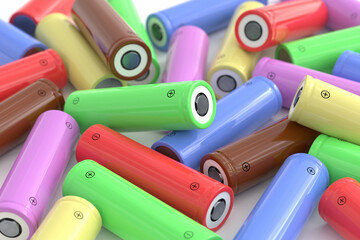 Lots of cylindrical batteries of different colors scattered on a white table. Lithium-ion...
