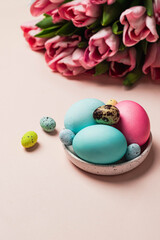 easter greeting card concept. bouquet of pink tulips with set of varios pastel colorful egss on pink backround. Easter background. top view with copyspace