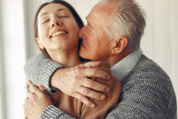 Elegant old man standing at home with his granddaughter