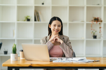 Beautiful business woman is using a laptop and smiling while working in office