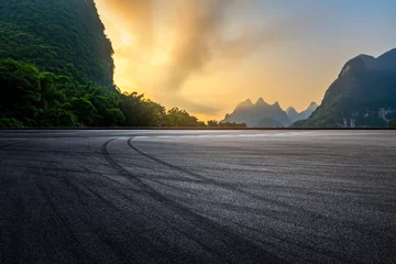 Foto op Plexiglas Guilin Asfaltweg en berg natuurlandschap bij zonsondergang. Weg en bergachtergrond.