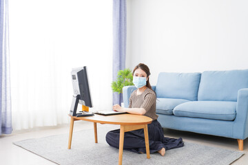 マスクをしてオンライン会議に参加する若いビジネスウーマン