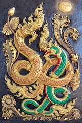 The stucco statue of Naga on the wall, with beautiful colors and details.