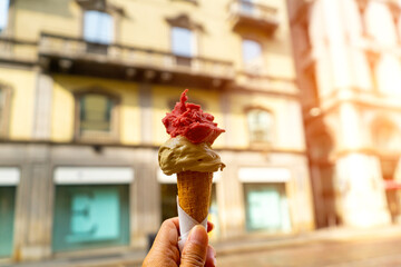 Green tea,strawberry and chocolate ice cream on the cone in row on the hand  with building and...