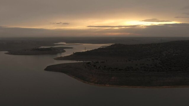 Aerial footage showing a beautiful sunset over a huge reservoir. The image pans to the left showing different areas of the water and beautiful reflections.