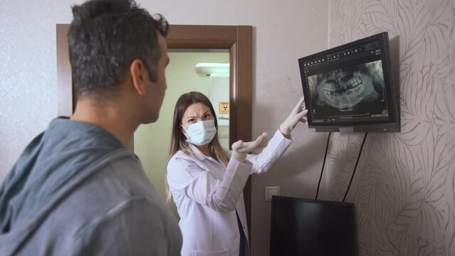 Dentist gives information to his patient via x-ray.
The dentist gives information about the mouth and teeth to the patient through x-ray.
