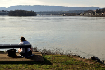 The woman spends time by a river who is relaxed  and watching the sunset.