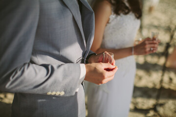 Close up view of a bride and groom holding a glass of sand in a wedding ceremony