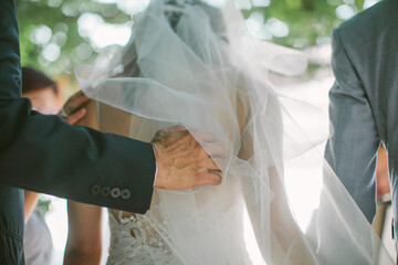 A father touching softly the back of her daughter, who is the bride, during a wedding ceremony
