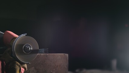 Forge workshop. Smithy manual production. Close up details, industrial worker using angle grinder and cutting steel. The blacksmith makes iron products for manufacture of fireplaces, stoves.