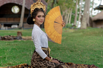 Beautiful young girl in yellow-white clothes posing with ancient fan